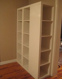 an empty room with white bookcases and hard wood floors