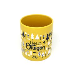 a yellow mug with the words hello oregon printed on it and trees in the background