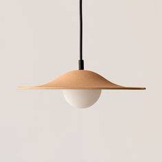 a light hanging from a ceiling with a white wall behind it and a black cord on the end