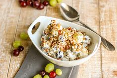 a bowl filled with grapes and nuts next to a spoon on top of a table