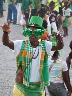 a man in a green hat and glasses dancing with other people on the sidelines