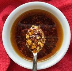 a white bowl filled with soup on top of a red cloth next to a spoon