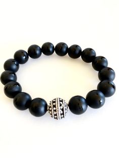 "Matte Tibetan black onyx stretch bracelet with beaded pewter focal bead accent. 10mm grade A Tibetan black onyx gemstones are matte with polished band through the middle. That are all natural stones. Accent is 12mm beaded Greek ball in antique silver pewter. Made in USA. Made to order on stretch elastic. When selecting size please add 3/4\" to 1\" to your actual wrist measurement for a comfortable fit. Black onyx is known as a powerful stone of protection." Black Stretch Bracelet With Spacer Beads As Gift, Spiritual Onyx Stretch Bracelet With Round Beads, Adjustable Onyx Stretch Bracelet With Gemstone Beads, Black Spiritual Stretch Bracelet With Polished Beads, Black Gemstone Beads Stretch Bracelet, Black Stretch Bracelet With Gemstone Beads, Onyx Gemstone Beads Stretch Bracelet, Black Adjustable Stretch Bracelet With Gemstone Beads, Adjustable Onyx Stretch Bracelet With Round Beads