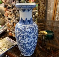 a large blue and white vase sitting on top of a table next to a pile of shells