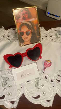 two heart shaped sunglasses sitting on top of a table next to a card and candy