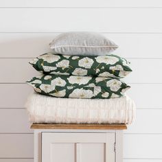 three pillows stacked on top of each other in front of a white wall and wooden cabinet