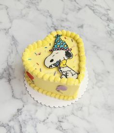 a cake shaped like a heart with a dog wearing a party hat on top of it