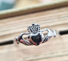 Introducing our exquisite collection of Irish handmade Claddagh rings, where tradition meets craftsmanship in every intricate detail. Each of our rings is a testament to the rich heritage and timeless elegance of the Claddagh symbol, originating from the shores of Galway, IrelandThe iconic Claddagh design, with its hands representing friendship, the crown symbolizing loyalty, and the heart signifying love, is flawlessly rendered in every ring. This timeless symbol serves as a reminder of the end Symbolic Intricate Design Jewelry For Anniversary, Symbolic Promise Ring With Intricate Design, Symbolic Intricate Design Promise Ring, Adjustable Crown Design Jewelry As Gift, Adjustable Crown Design Jewelry For Gift, Symbolic Ring With Intricate Design For Promise, Traditional Silver Promise Ring, Crown Design Open Ring Jewelry Gift, Traditional Adjustable Rings For Anniversary