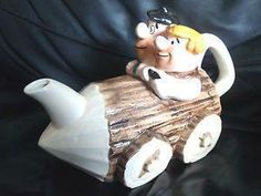 a ceramic figurine of a man riding on a wooden log with a teapot