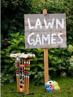 a lawn game sign sitting in the grass next to some balls and croquets