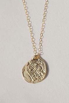 Reversible double sided Medallion charm necklace made from an old Spanish coin. A gorgeous and detailed gold necklace perfect for any occasion. Cast from an original ancient coin, the Medallion Necklace was designed to attract growth, fortune, and opportunity. Coins have a long history of bringing good luck and have become a symbol of prosperity and wealth. Throwing coins into a wishing well is a tradition that predates recorded history. A silver coin was used under the mast of a ship as it was Gold Amulet Style Coin Necklace, Amulet Style Coin Necklace As Gift, Brass Coin Necklace Gift, Coin Shaped Charm Necklace Gift, Yellow Gold Medallion Necklace With Coin Pendant, Brass Coin Pendant Necklace For Gift, Gold Plated Coin Necklace Styled As Amulet, Amulet Style Medallion Necklace With Coin Pendant, Amulet Coin Necklace For Gift