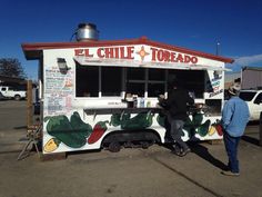 two people are standing in front of a food truck that is painted with chilis