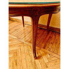 a wooden table sitting on top of a hard wood floor next to a wall with a green glass top