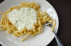 a white plate topped with pasta covered in sauce and parmesan cheese on top