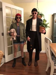 a man and woman dressed in costumes standing next to each other near a table with potted plants