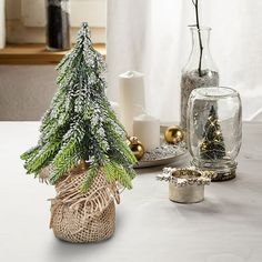 a small christmas tree sitting on top of a table next to other holiday decorations and candles