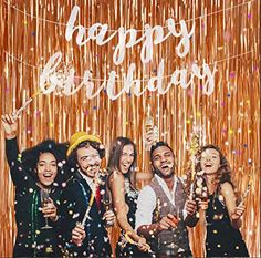 a group of people standing next to each other under a happy birthday sign