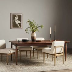 a dining room table with chairs and a vase filled with flowers on top of it