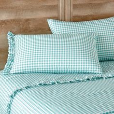 a blue and white checkered comforter set on a wooden headboard in a bedroom