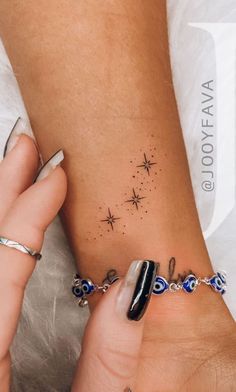 two hands holding each other with tattoos on their wrist and one has a star tattoo on it