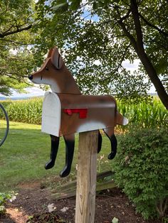 a mailbox shaped like a dog sitting on top of a wooden post