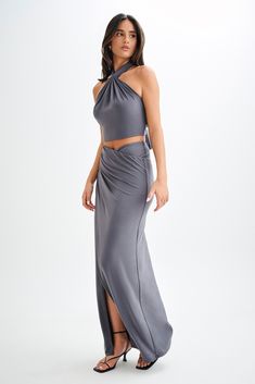 For a summer escapade.The BRONWYN Slinky Ruched Maxi Skirt With Split is a sophisticated and stylish piece designed to make a statement. Featuring a mid-rise fit and a flattering V front, this skirt enhances your natural curves. The centre front split adds a touch of allure, while the ruching at the side seams provides a chic, textured look. Made with stretch fabrication, it ensures comfort and ease of movement. For a complete and stunning outfit, pair this skirt with the Bronwyn Slinky Halter C Capsule Wardrobe Accessories, Skirt With Split, European Summer Outfits, Wardrobe Accessories, Capsule Outfits, Beige Dresses, Stunning Outfits, Halter Crop Top, Natural Curves