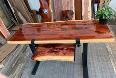 a wooden table sitting on top of a metal stand next to a potted plant