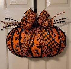 an orange and black pumpkin hanging on a door with beaded beads around the edges