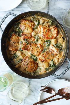 chicken and spinach casserole in a skillet with utensils on the side