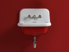 a red and white bathroom sink with two faucets on it's side