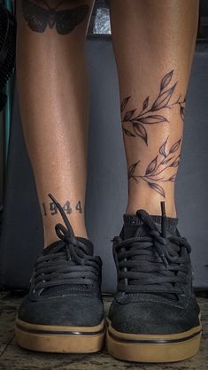 the legs and ankles of a person with tattoos on them, both wearing black sneakers