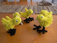 four yellow birds sitting on top of a wooden table