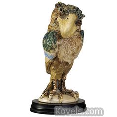 an owl figurine is sitting on top of a black and white base with gold accents