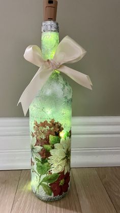 a bottle with flowers painted on it and a bow around the top is sitting on a wooden floor