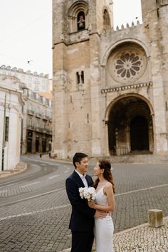 a bride and groom standing in front of an old church