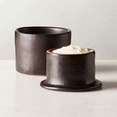 two black pots with whipped cream in them