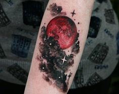 a red moon tattoo on the arm with stars and clouds around it in black ink