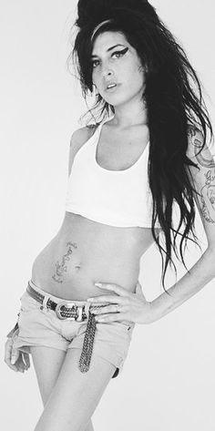 a woman with tattoos on her stomach posing for a photo in front of a white background