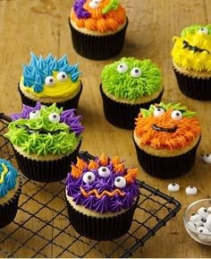 cupcakes decorated to look like monsters on a cooling rack