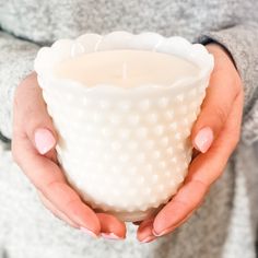 a woman holding a white candle in her hands