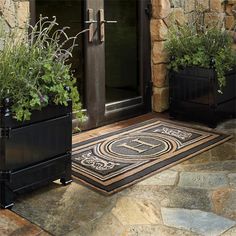 two black planters with plants in them are on the front porch