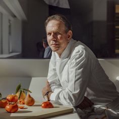 a man sitting in front of a cutting board with tomatoes on it