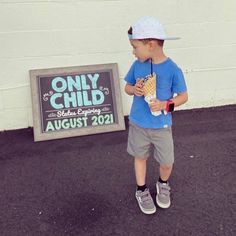 a little boy standing in front of a only child sign holding an ice cream cone