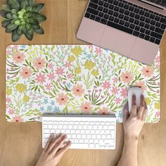 a person using a mouse and keyboard on a desk with flowers printed on the surface