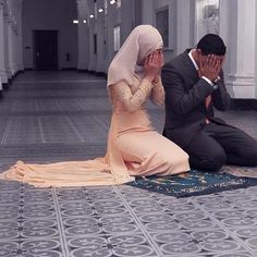 a man and woman sitting on the floor covering their faces with hands while they are praying