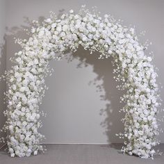 a white flowered arch is shown in front of a gray wall