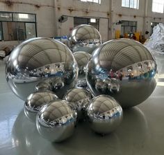 several shiny metal balls are stacked on top of each other in a large room with lots of windows