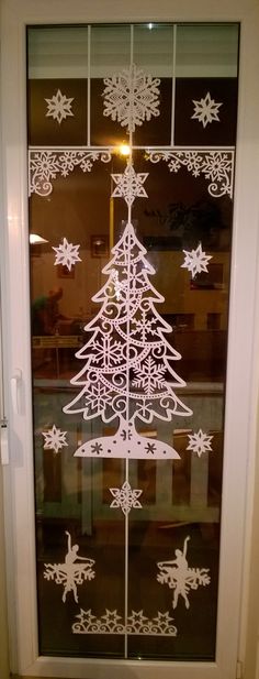 a glass door decorated with white snowflakes and a christmas tree on the side