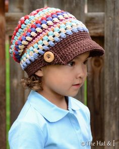 a little boy wearing a crocheted hat with buttons on it's brim