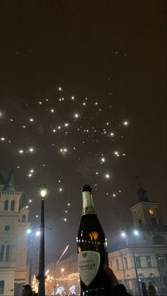 a bottle of beer is being held up in the air with fireworks coming from it